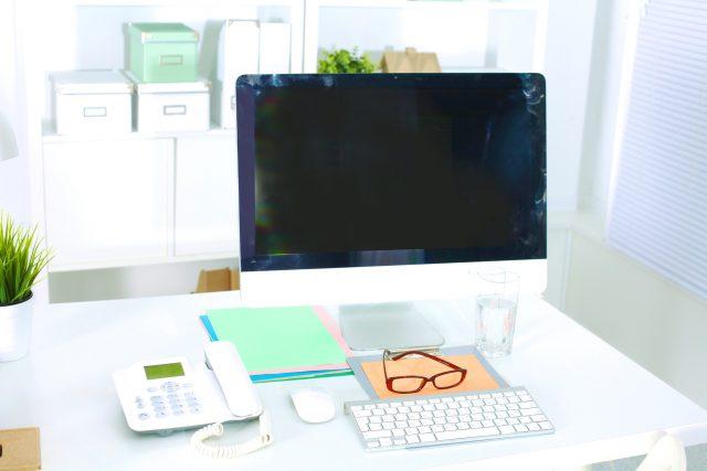 Office table with blank notepad and laptop